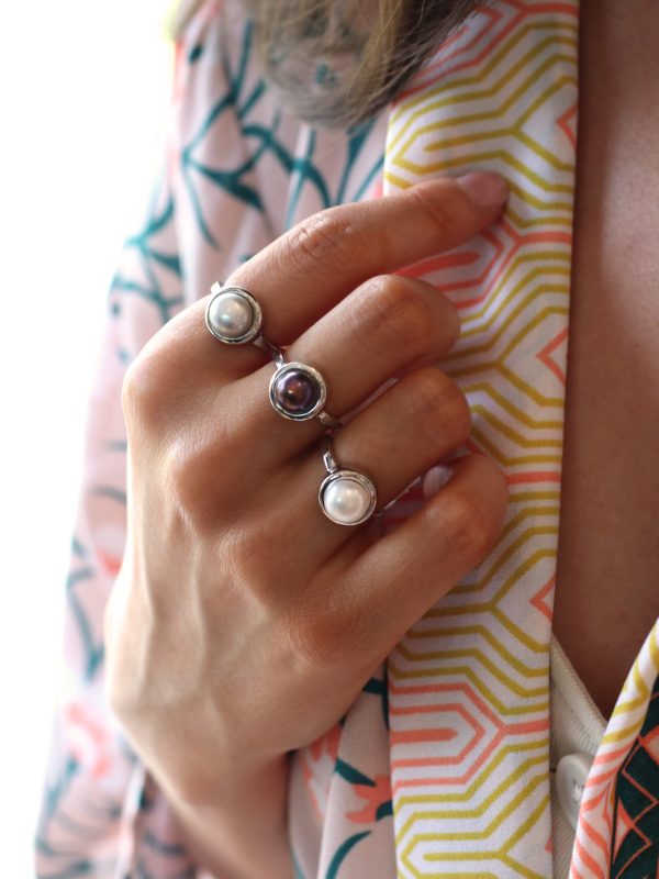 Model wearing Jersey Pearl Freshwater button pearl silver rings - white, peacock and grey